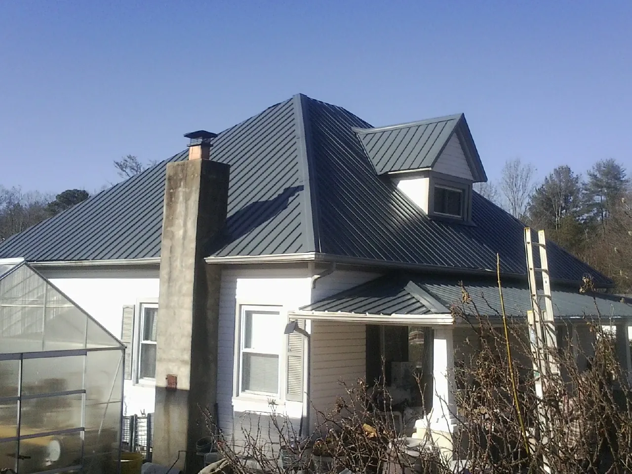 Dark blue standing seam metal roof on a white farmhouse with dormer — Slate & Tile Roof Repair by Roofing Brothers in Basking Ridge