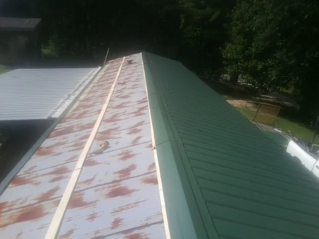 Old rusted panels beside newly installed green metal roofing — Wind Damage Roof Repair by Roofing Brothers in Basking Ridge