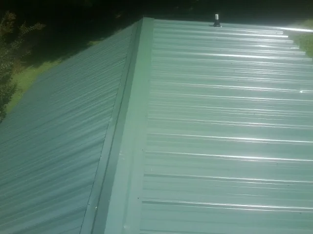New green metal panels meeting at the ridge of a roof — Flat Roof Repair work by our crew in Basking Ridge