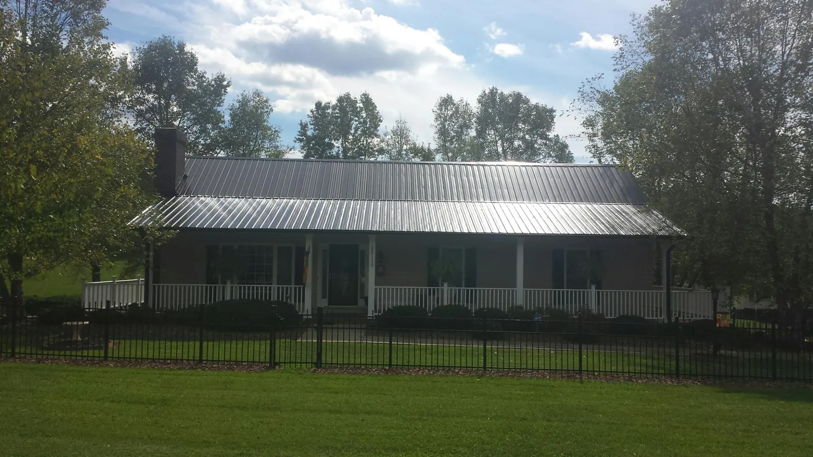 Gray metal roof on a brick ranch with a full width front porch — Gutter Guard Installation work by our crew in Basking Ridge