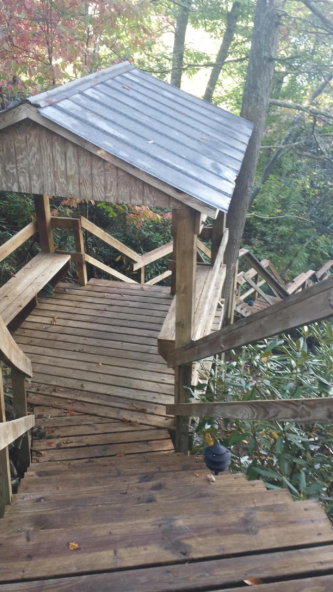 Metal roofed shelter over wooden steps on a wooded walkway — Skylight Repair & Installation work by our crew in Basking Ridge