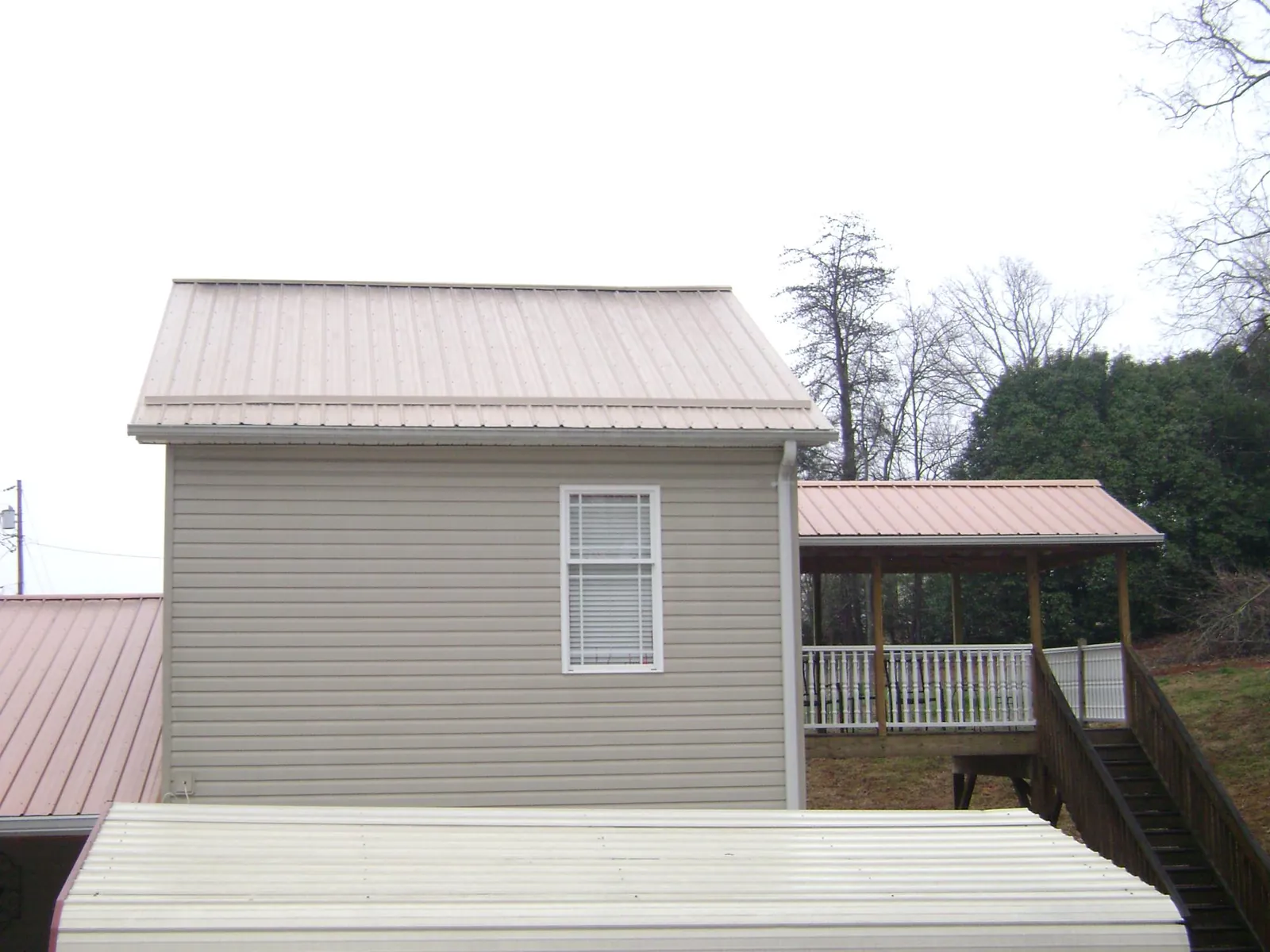 Tan metal roofs on a two story addition and attached porch, from a Roof Replacement job in Basking Ridge