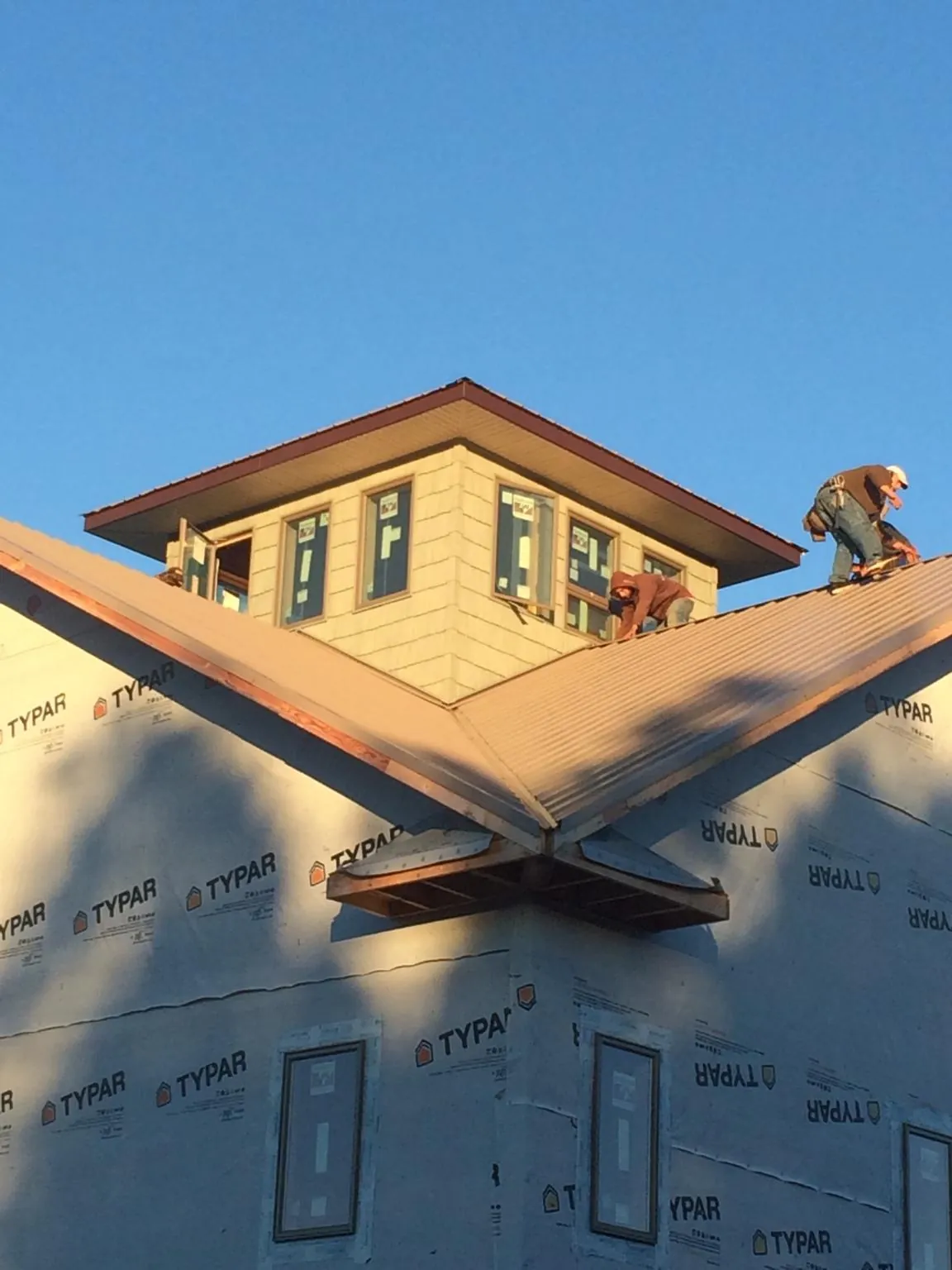 Roofers working around a rooftop cupola on a new metal roof at sunset — Roof Waterproofing in Basking Ridge by Roofing Brothers